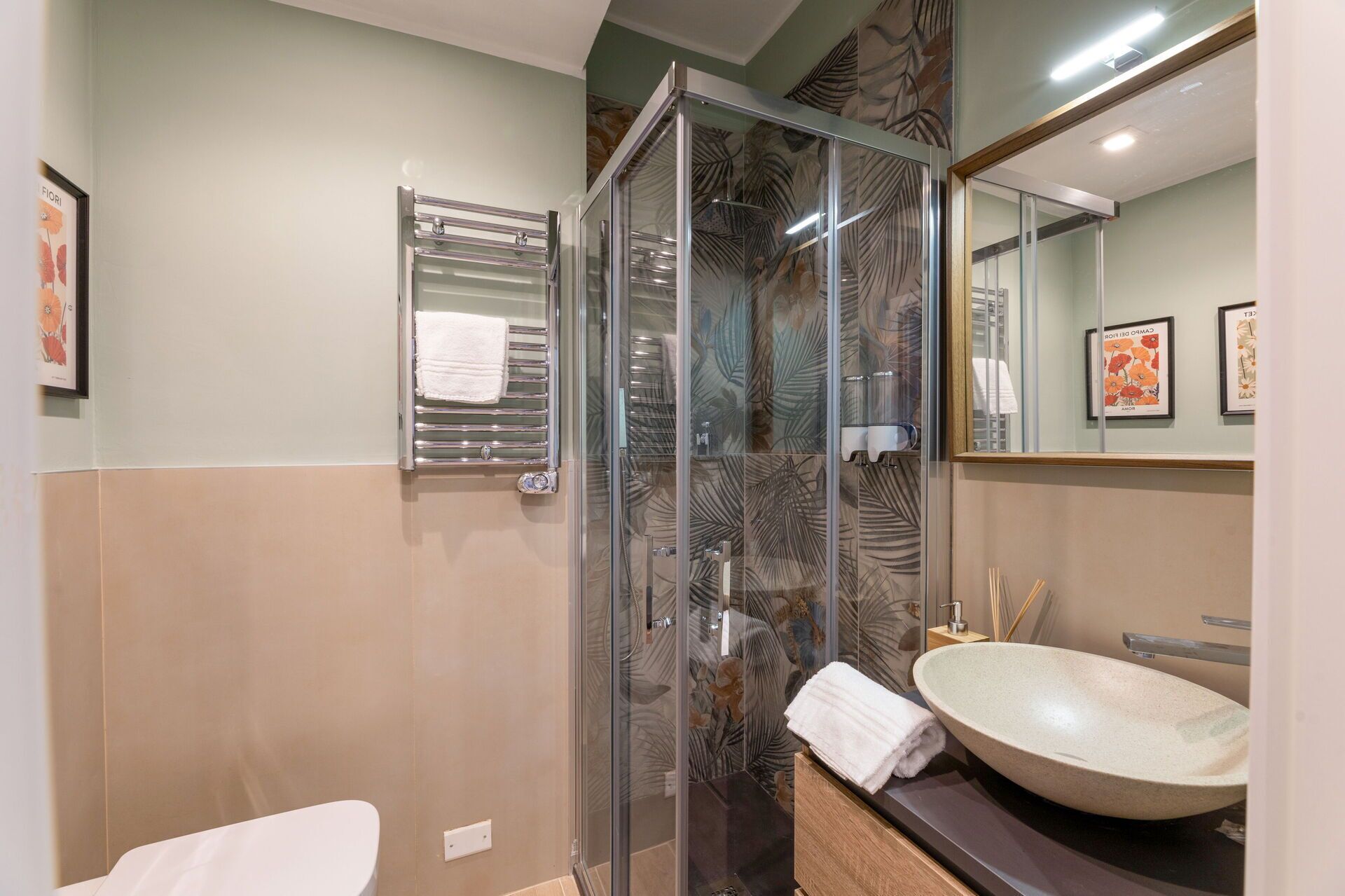 Une salle de bain moderne avec une douche à parois de verre, un lavabo blanc et un porte-serviettes.