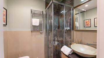 Une salle de bain moderne avec une douche à parois de verre, un lavabo blanc et un porte-serviettes.