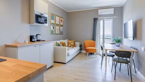 A compact living space with a kitchenette, a dining area, and a seating area with a sofa and chairs. - Italian Experience- Suite MareConero (Porto Recanati)