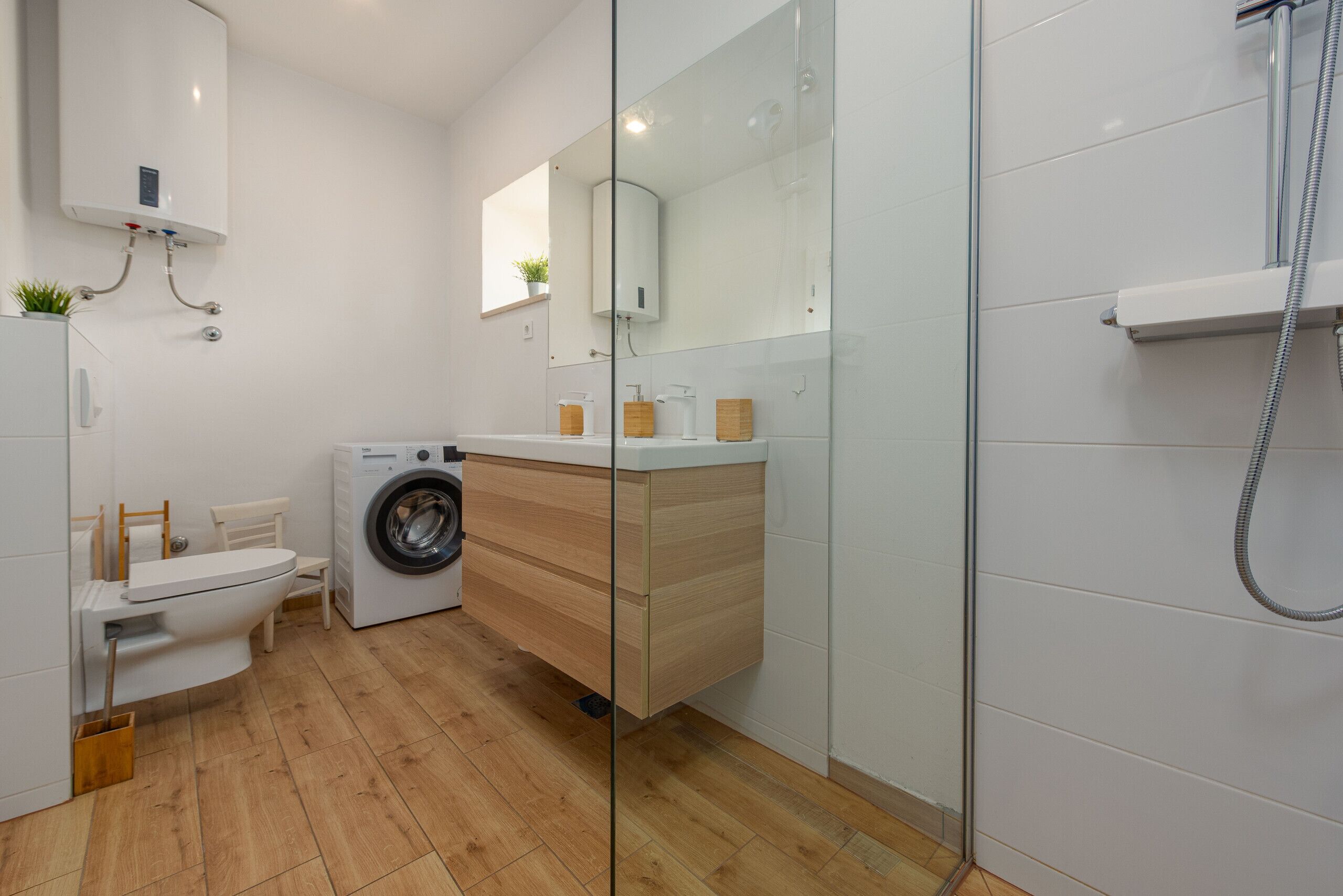 Un baño moderno con lavadora, inodoro y cabina de ducha de vidrio.