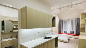A modern hotel room with a marble bathroom, a bed with a red headboard, and a seating area with curtains. - CC Xanh Xanh (Xuan Huong - Da Lat)