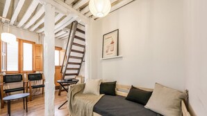 A cozy room with a wooden bed, a wooden bench, a small table, and a staircase. - Charming Central Madrid Loft (Madrid)