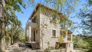 Una casa de piedra con un balcón, una escalera y un jardín.