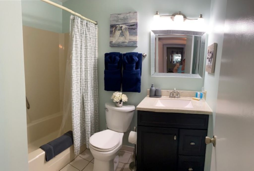 A bathroom with a shower, toilet, sink, and dark cabinets.