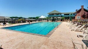 Una piscina con sillones de descanso y una zona techada.