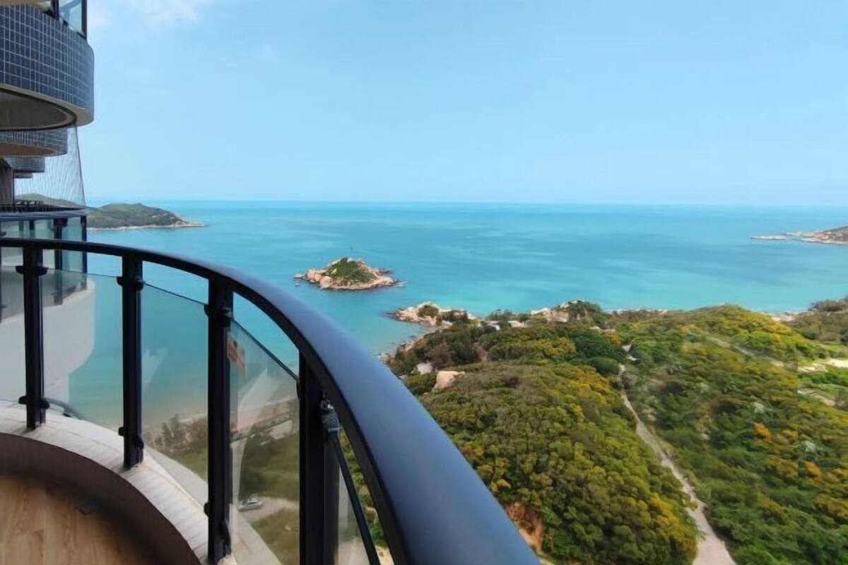 Un punto elevado con vistas a un paisaje costero, que incluye una pequeña isla y abundante vegetación.