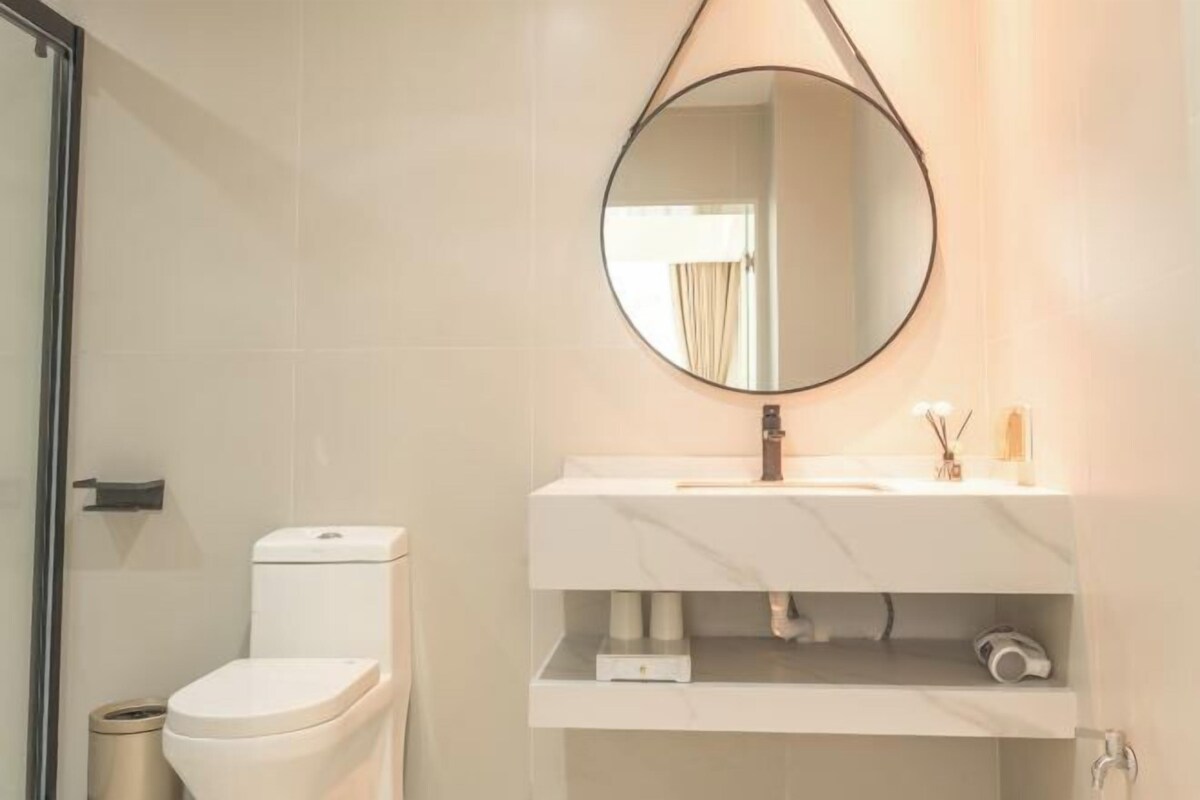 A bathroom with a toilet, a sink with a mirror, and a shower area.
