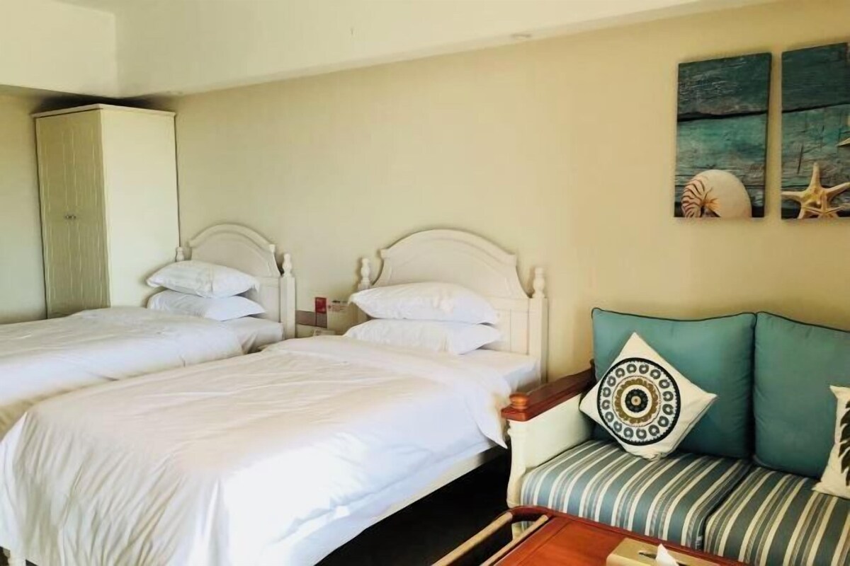 A hotel room with two single beds, a sofa, and a wall painting.