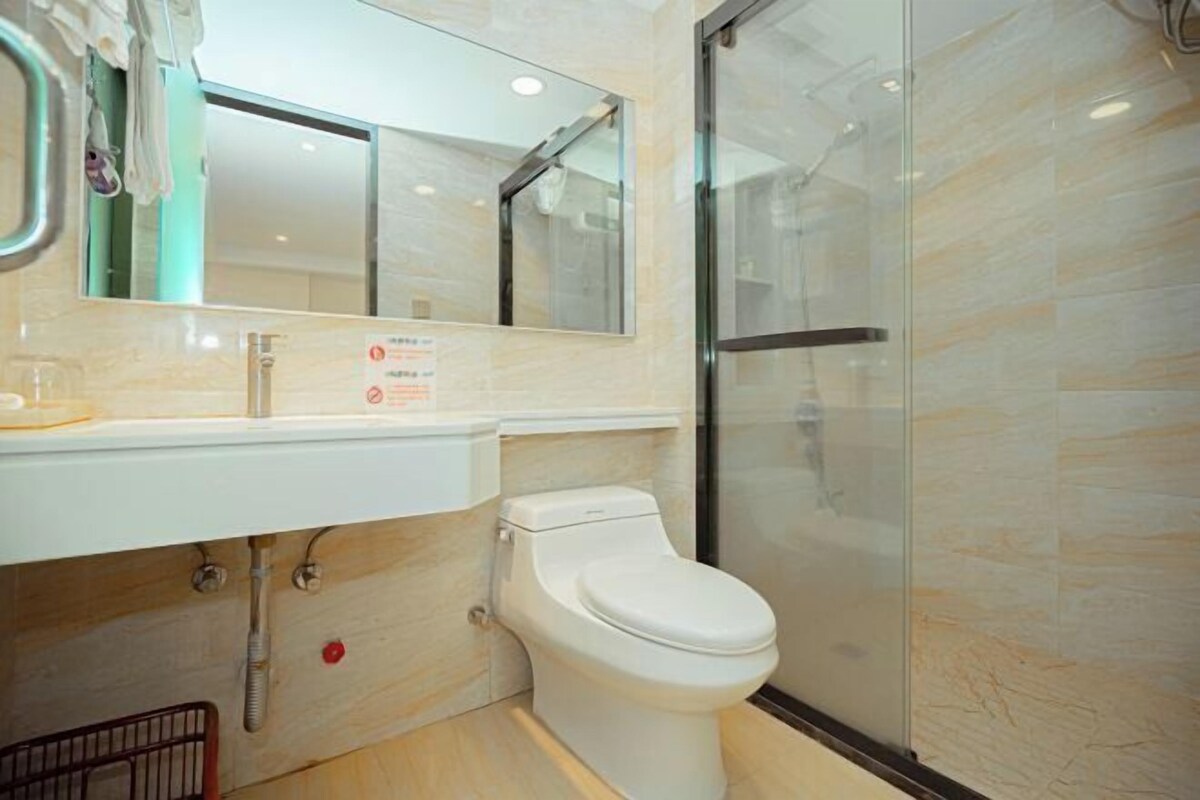 A modern bathroom with a white toilet, a glass shower enclosure, and a mirror above the sink.