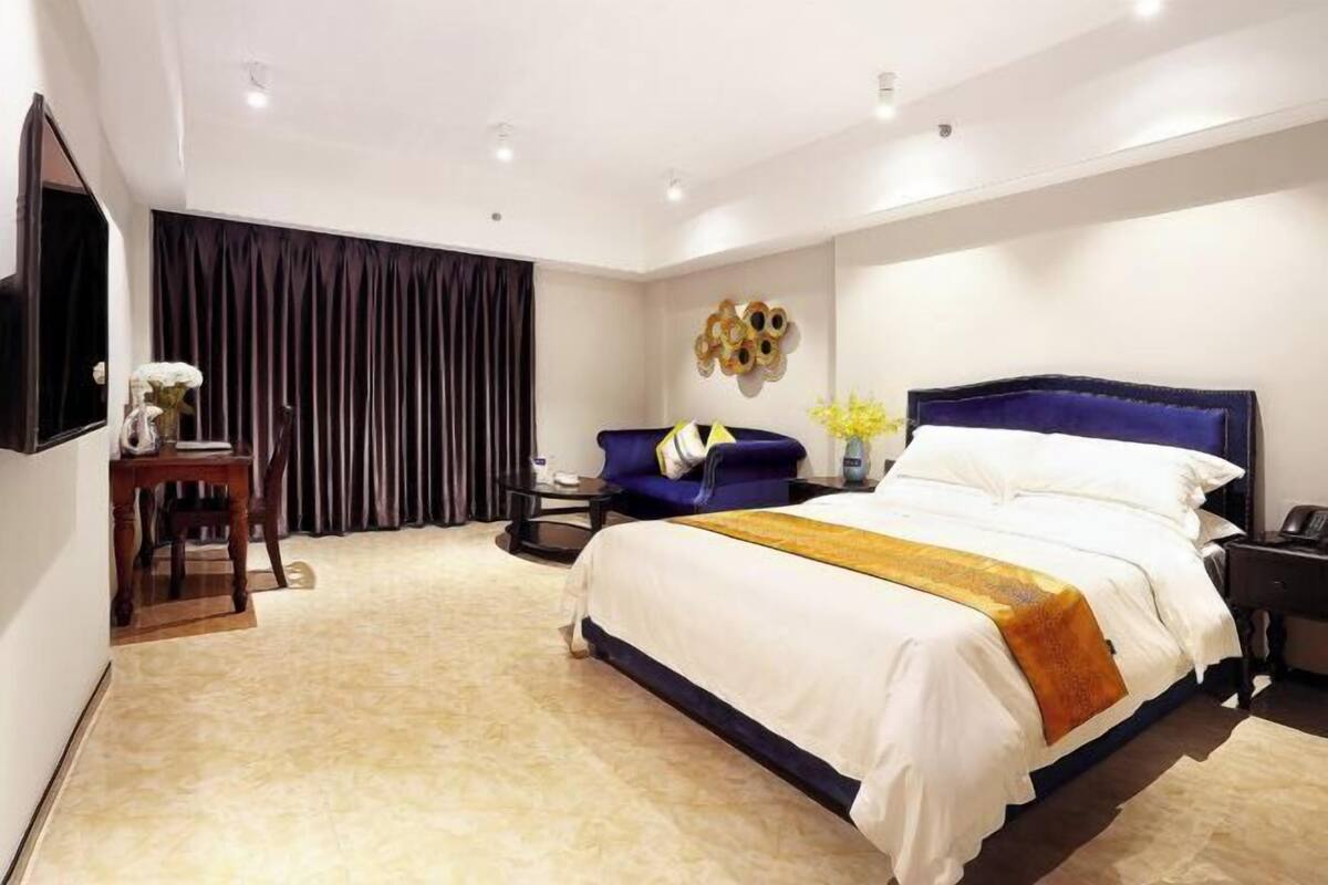 Una habitación de hotel moderna con una cama grande, un escritorio, una silla, un televisor de pantalla plana y un elemento decorativo en la pared.
