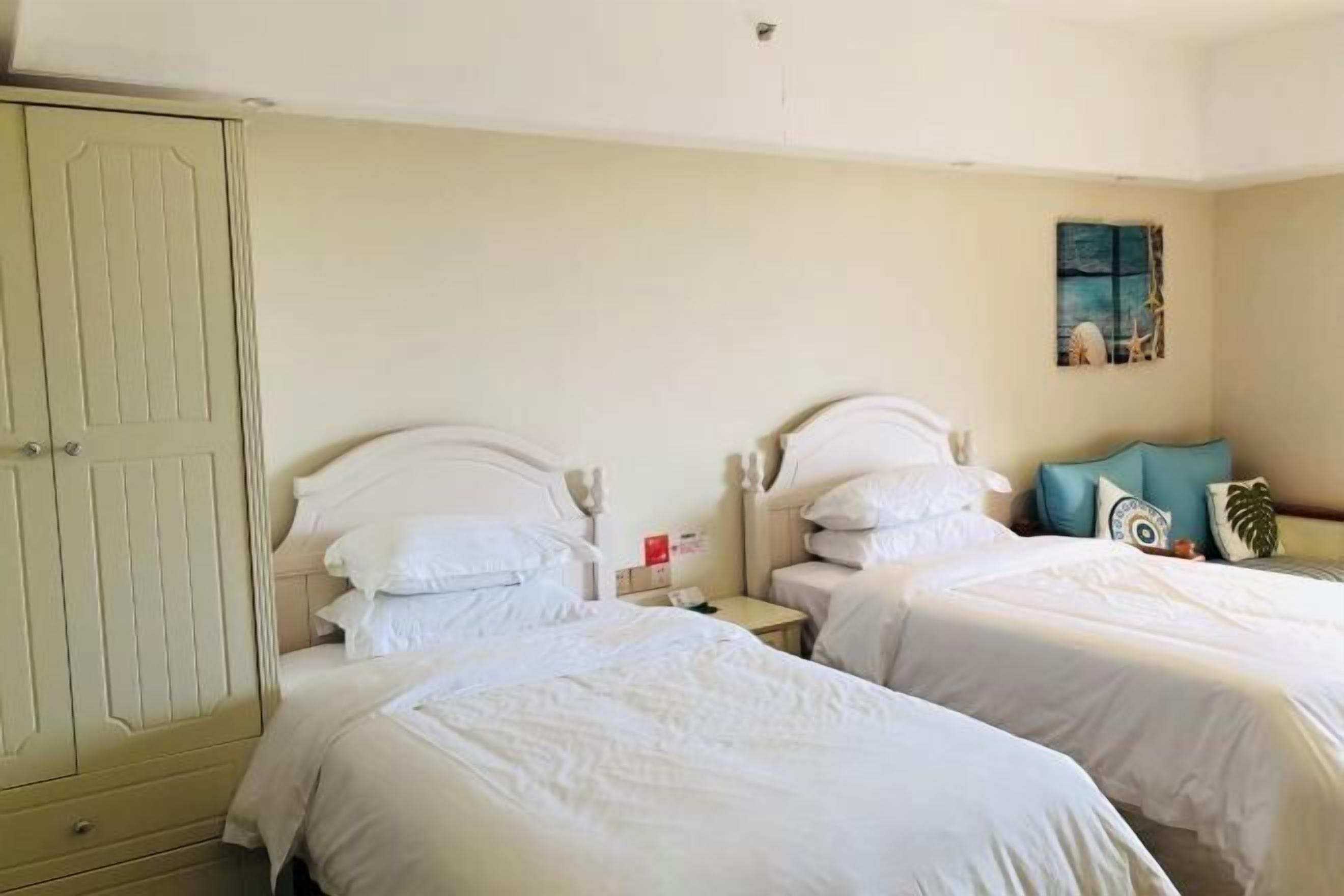 A hotel room with two beds, a wardrobe, and a painting on the wall.