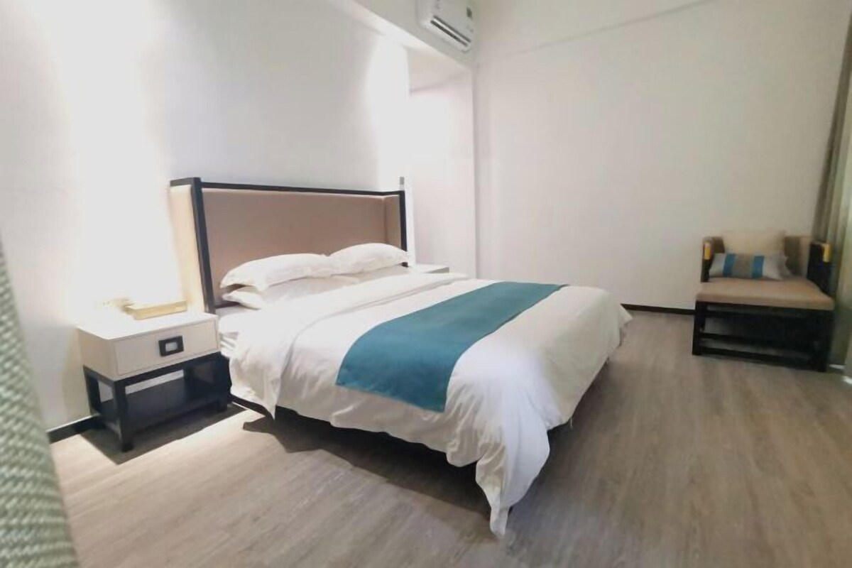A hotel room with a bed, bedside table, and a chair.