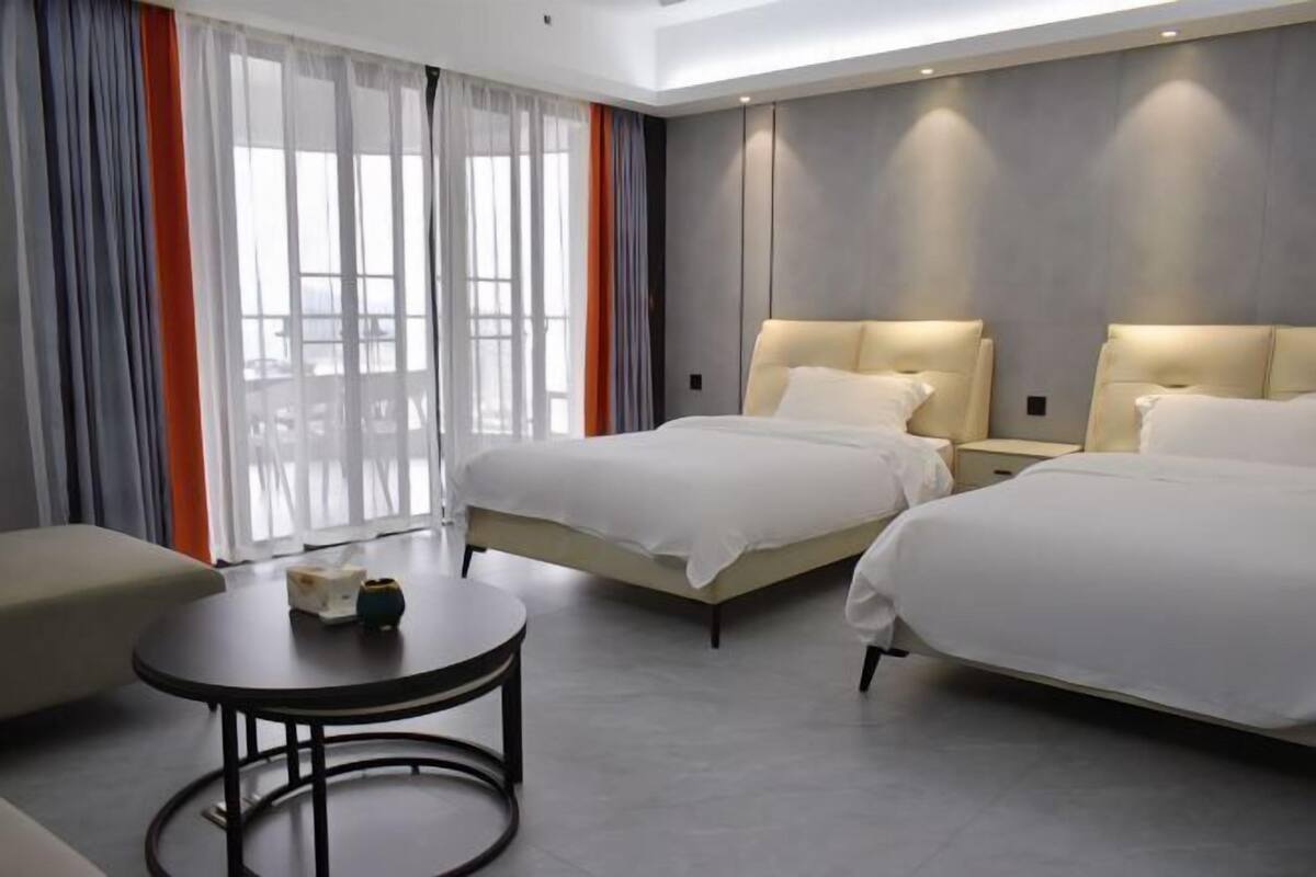Habitación de hotel con dos camas, una mesa redonda y un sofá.