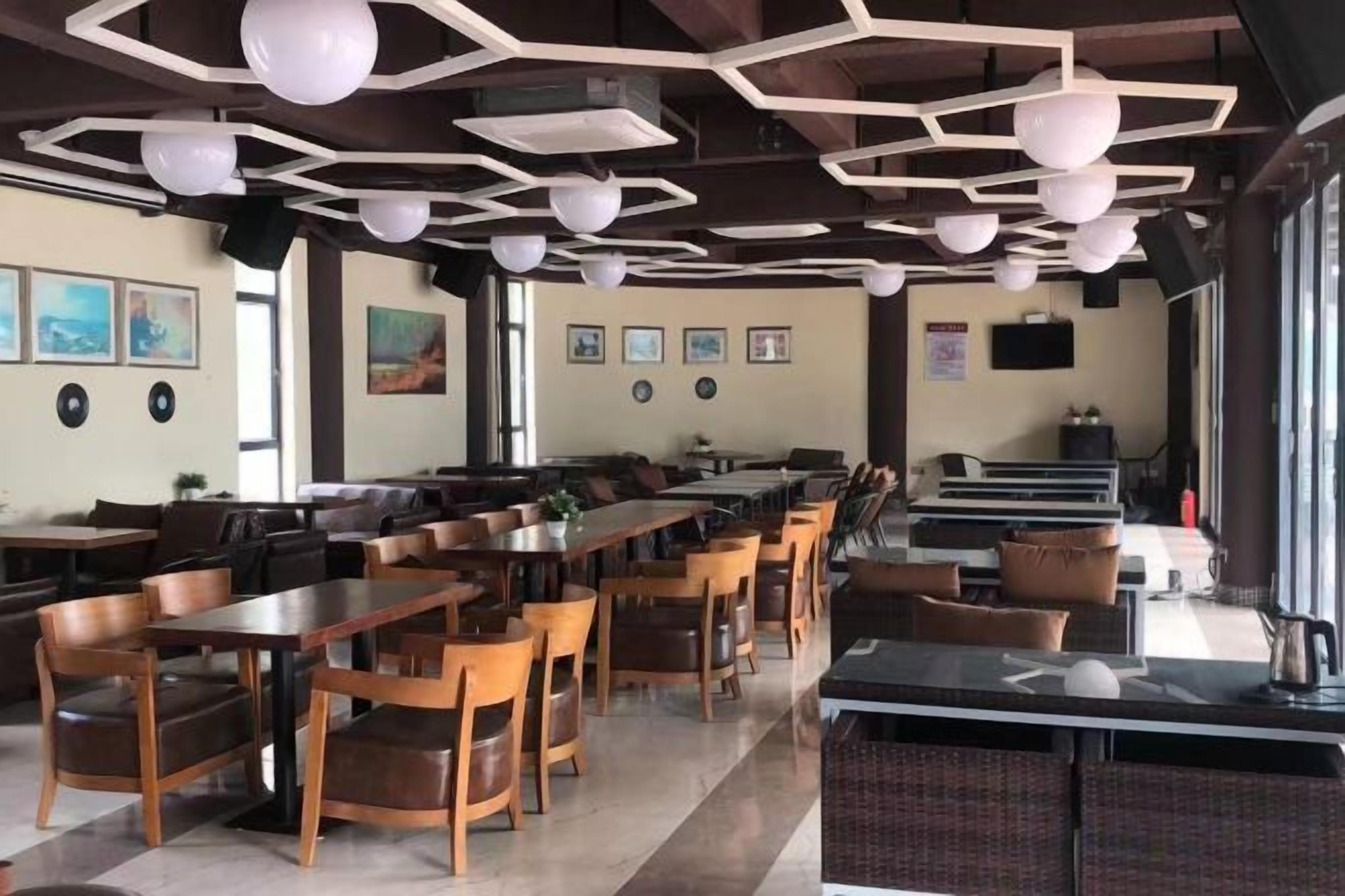 Un restaurant doté de nombreuses tables et chaises, d’un comptoir et d’un espace détente avec des canapés.