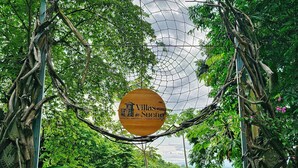 Un letrero de madera con la leyenda "Villas en Suneo" y "Manuel Antonio - Costa Rica", colgando entre árboles.