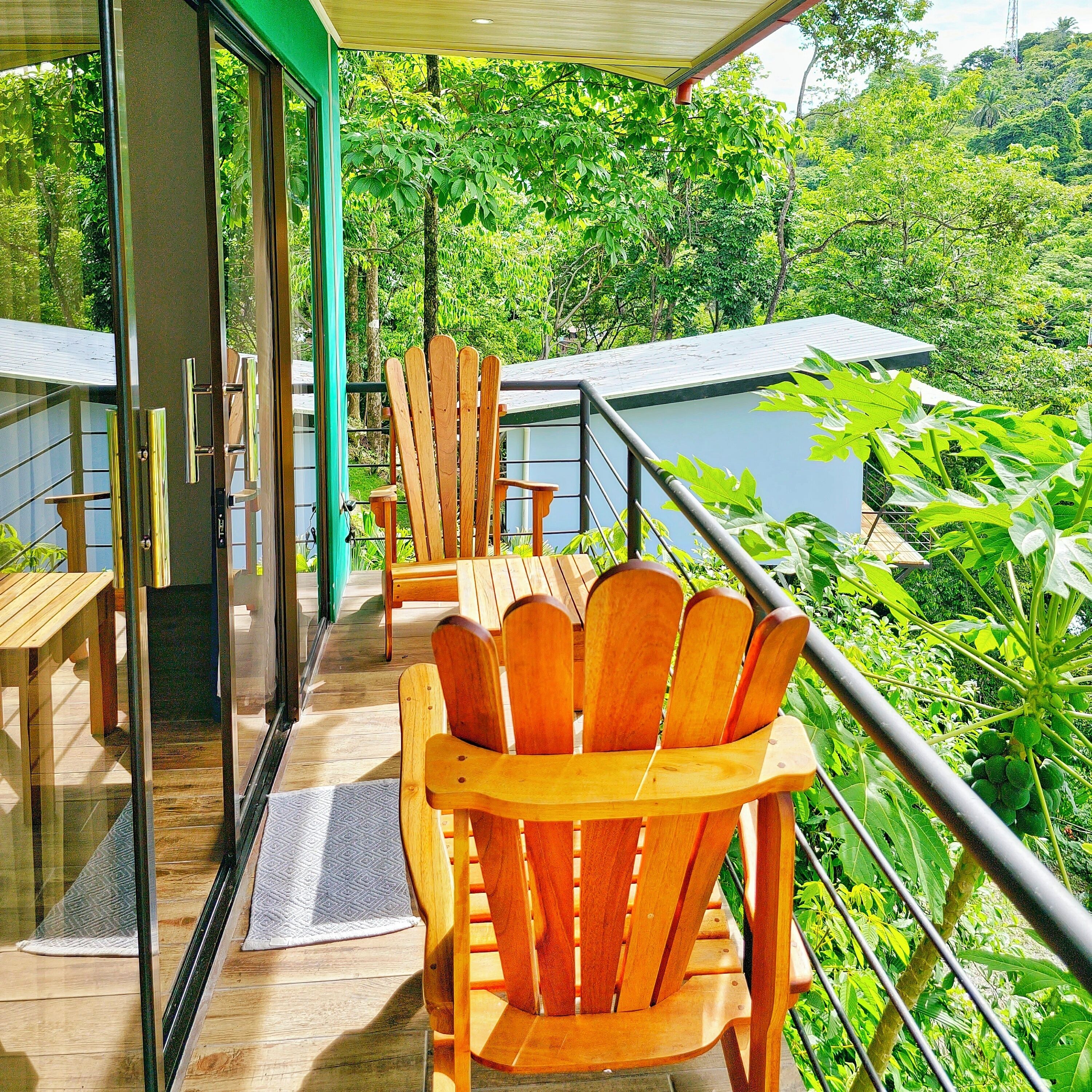 A wooden deck with chairs and tables, overlooking a lush green landscape.