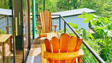 A wooden deck with chairs and tables, overlooking a lush green landscape.