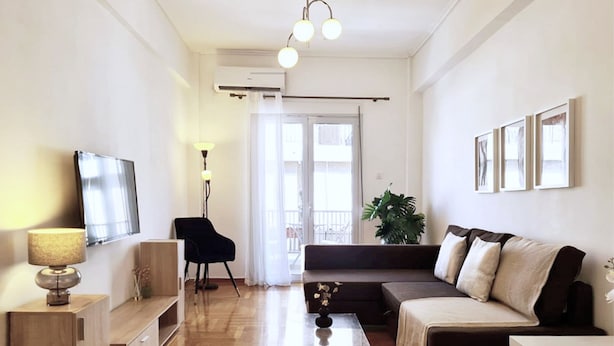 Ein modernes Wohnzimmer mit Sofa, Couchtisch, Fernseher und einer Pflanze.