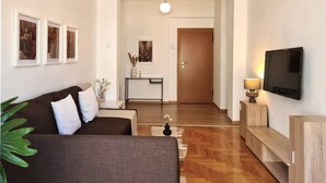 Ein modernes Wohnzimmer mit einer Couch, einem Couchtisch, einem Fernseher und Holzboden.
