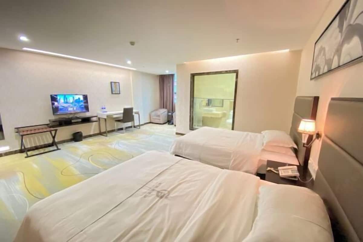 A hotel room with two beds, a TV, a desk, and a chair.