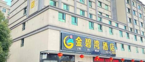A hotel with a prominent sign, multiple floors, and a storefront with visible windows.