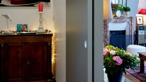 A modern living room with a fireplace, a dining area with a table and chairs, and a hallway with a coat rack. - Latin Quarter - Jardin des plantes (Paris)