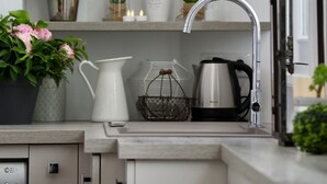 A kitchen with a sink, a coffee maker, a kettle, a basket, a potted plant, and a bottle of Coca-Cola. - Latin Quarter - Jardin des plantes (Paris)