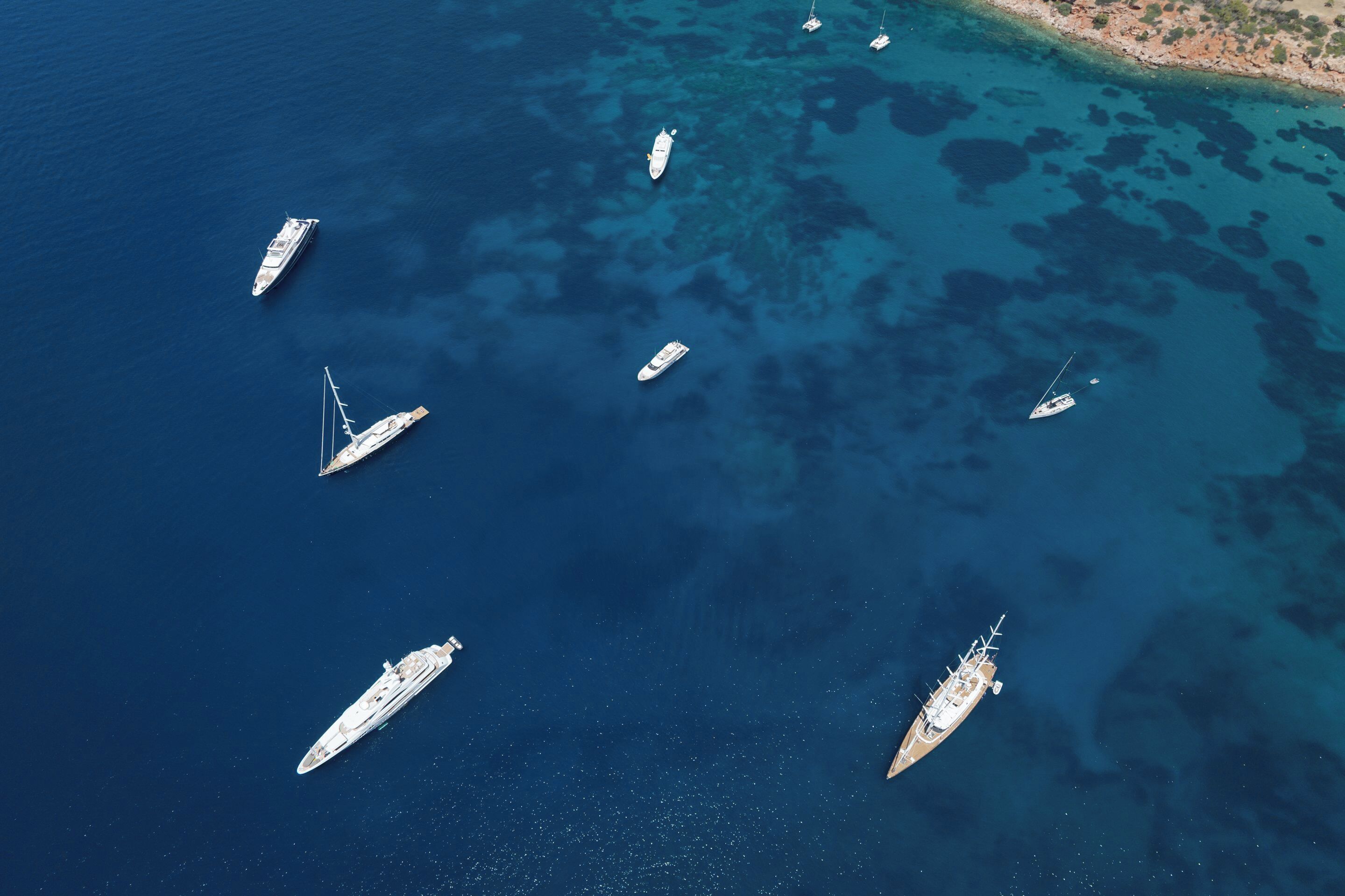 Vista aérea de un puerto deportivo con varios yates anclados en aguas azul cristalino.