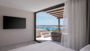 Ein modernes Hotelzimmer mit einem großen Bett, einem Flachbildfernseher und einem Balkon mit Meerblick.
