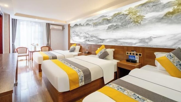 A hotel room with two beds, a desk, and a large wall mural. - Kunming Xiangyi Business Hotel (Kunming)