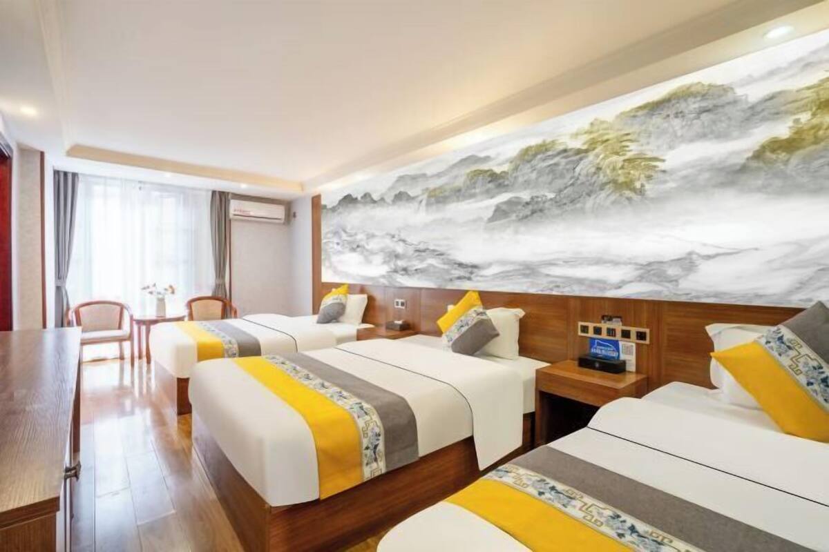 A hotel room with two beds, a desk, and a large wall mural.