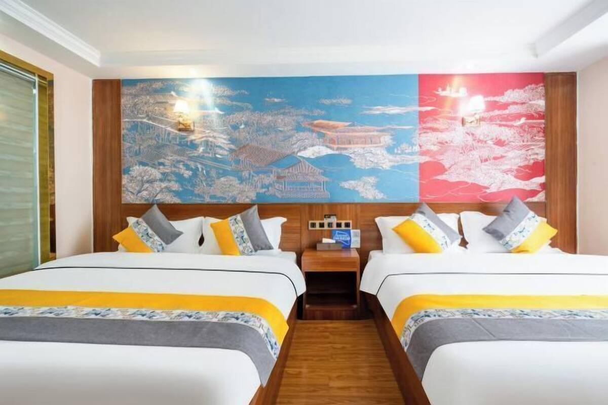 A hotel room with two beds, a wooden headboard, and a large cityscape mural on the wall.