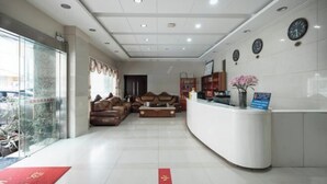 A hotel lobby with a reception desk, seating area, and a large window with a view of the outside. - Kunming Xiangyi Business Hotel (Kunming)