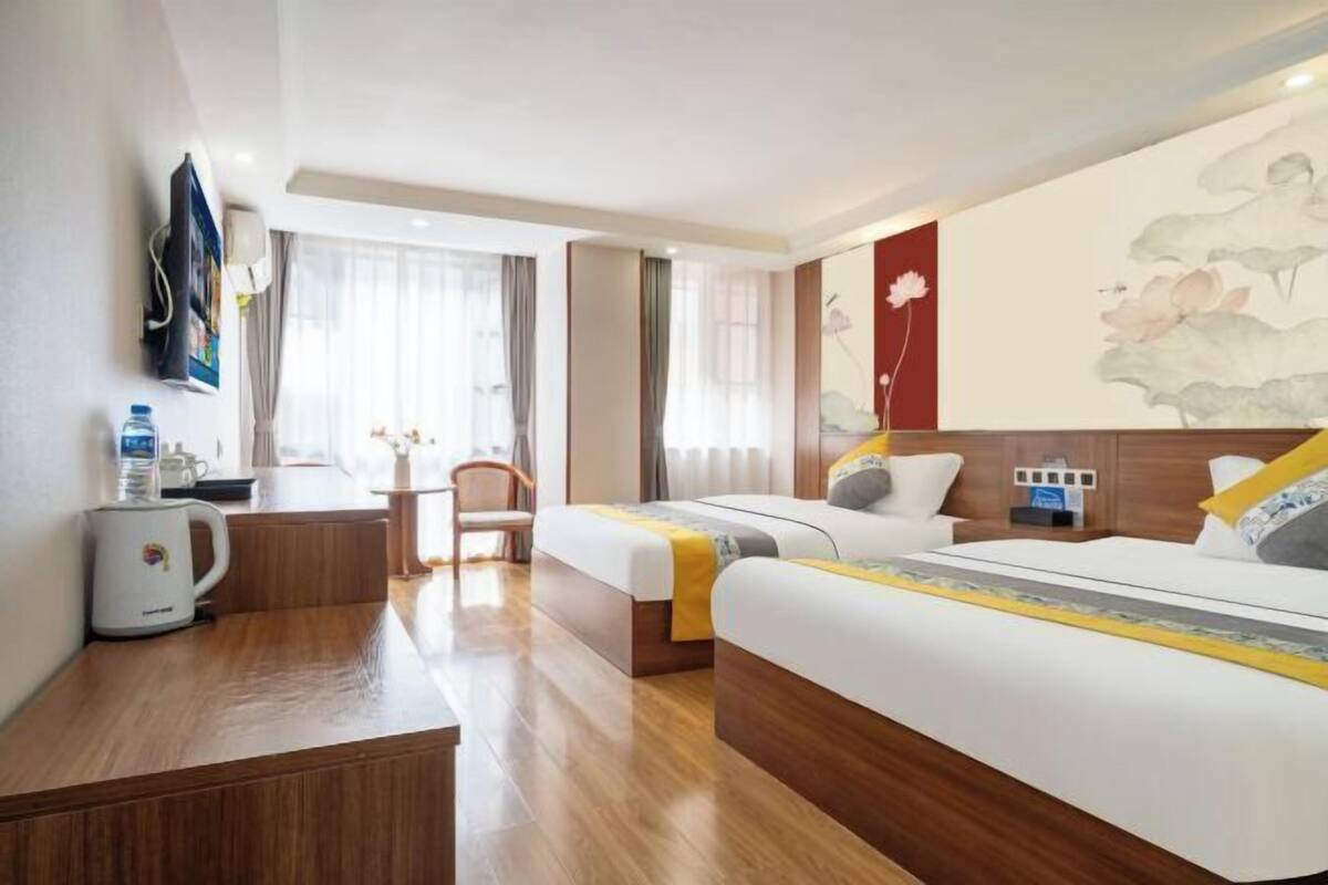 A hotel room with two beds, a desk, a chair, a coffee maker, and artwork on the walls.