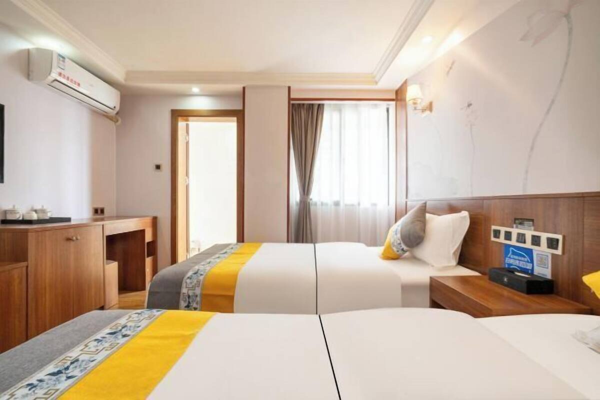 A hotel room with two beds, a desk, and a wardrobe.