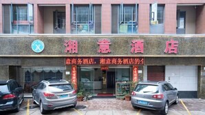 A hotel entrance with a signboard, two parked cars, and a red awning. - Kunming Xiangyi Business Hotel (Kunming)