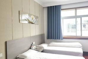 A hotel room with two beds, a nightstand, a wall-mounted mirror, and a window with curtains. - Xiuning Limin Hotel (Xiuning)