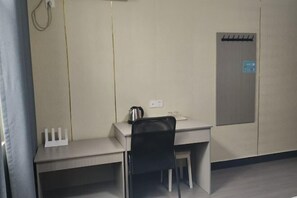 Una oficina pequeña y privada con un escritorio, una silla y un perchero.