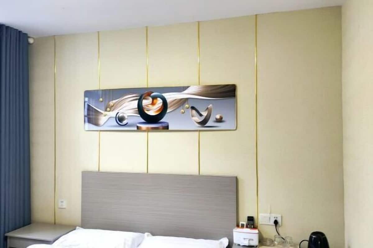 Habitación de hotel con cama, mesita de noche y un cuadro abstracto colgado en la pared.