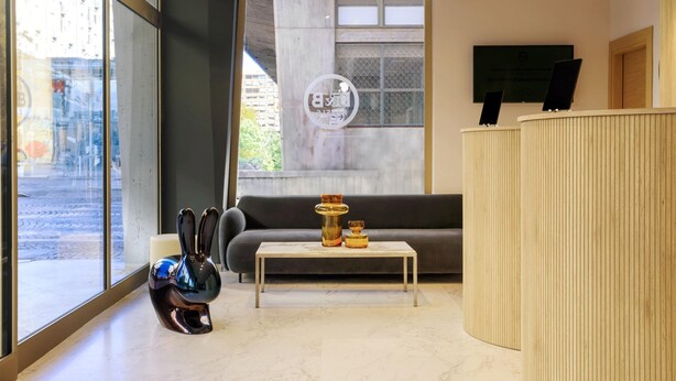 Una recepción moderna con un sofá, una mesa de centro y un muro de cristal que ofrece vistas a la calle.