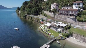 Ein Hotel am Seeufer mit Steg, Booten und einer Reihe von Liegestühlen.