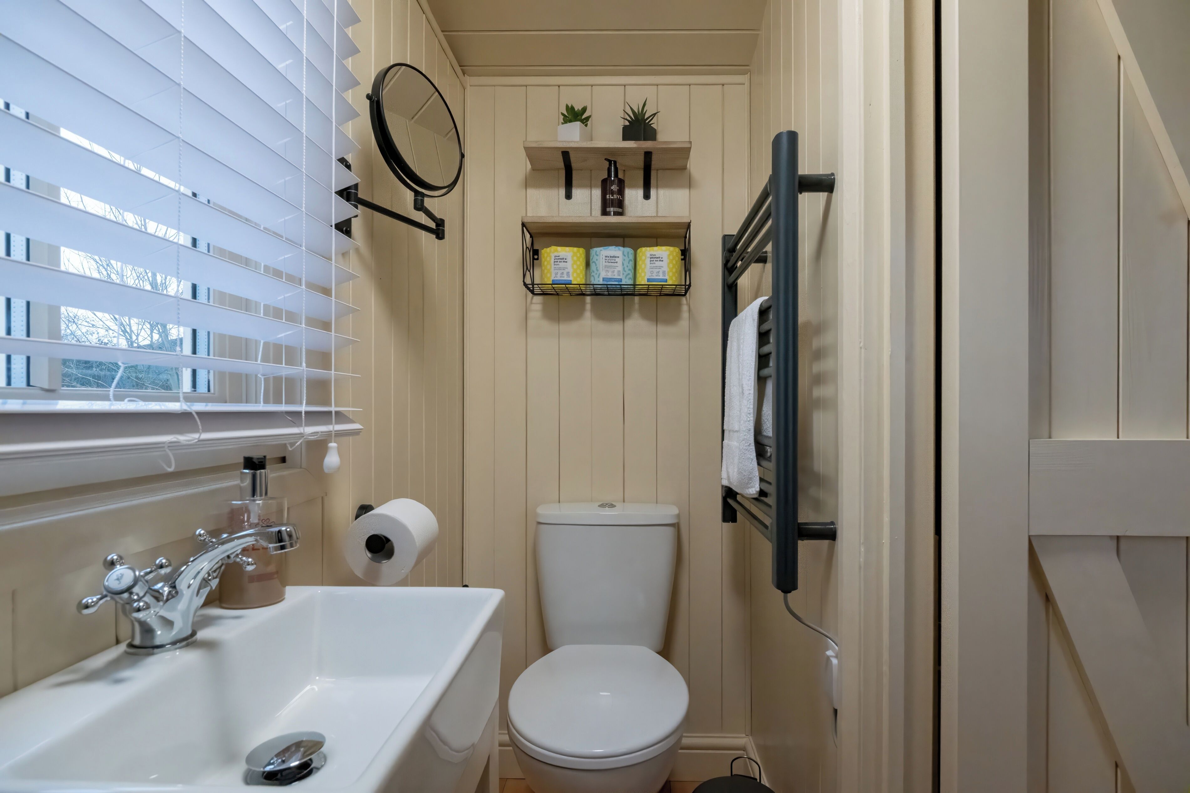 A compact bathroom with a white sink, toilet, and window blinds.