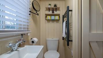 A compact bathroom with a white sink, toilet, and window blinds.