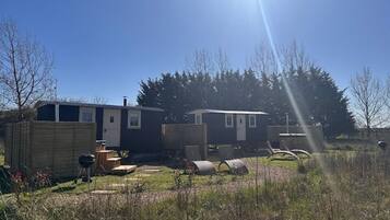 A mobile home with a fenced yard, a barbecue grill, and a small shed.