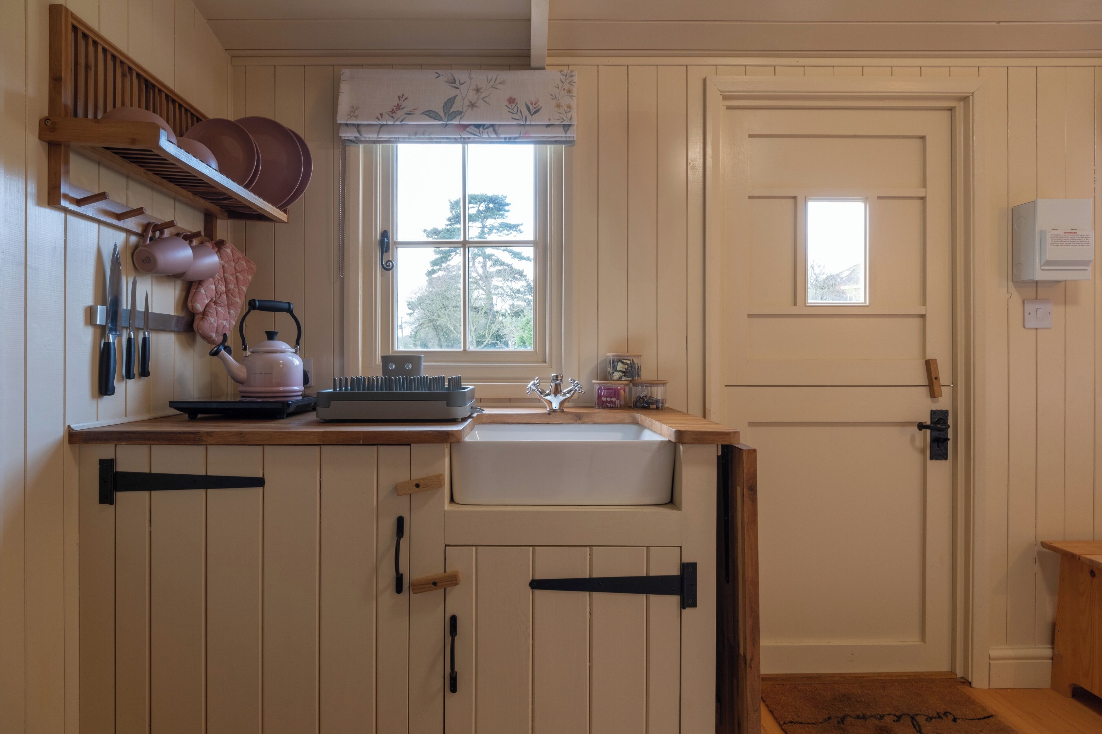Una cocina con un lavamanos, armarios de madera, una ventana y una puerta.