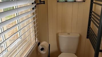 A compact bathroom with a toilet, sink, and window blinds.