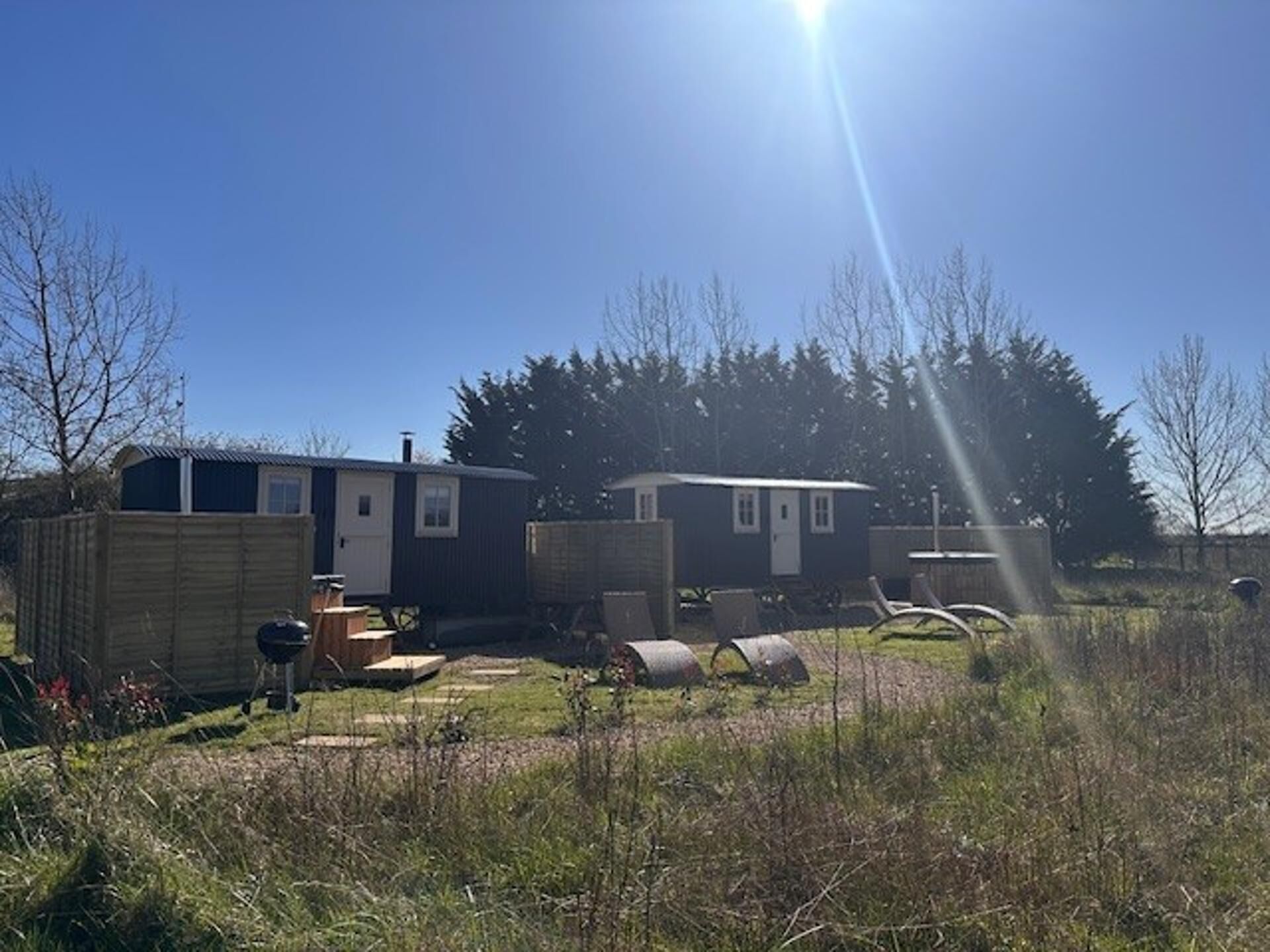 A mobile home with a fenced yard, a barbecue grill, and a small shed.