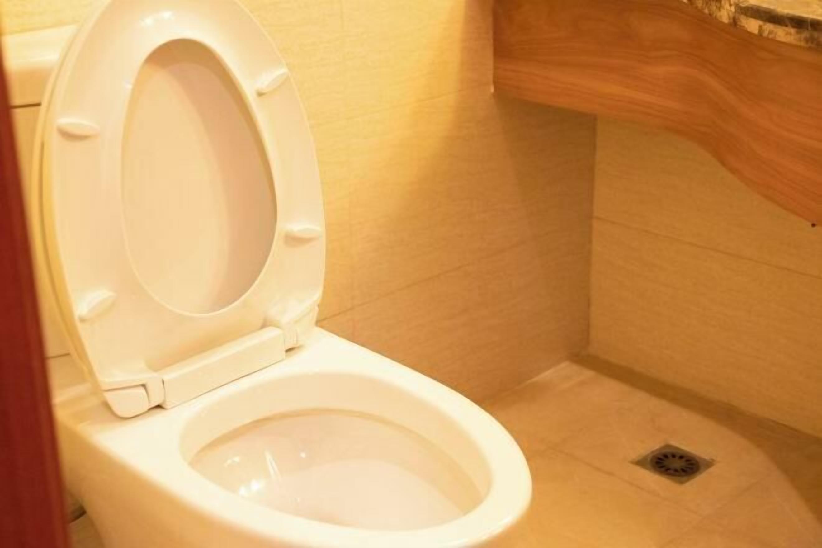 A white toilet in a bathroom with a wooden vanity and a tiled floor.