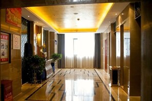 A hotel lobby with a polished floor, a reception desk, and a large window at the end of the corridor. - Haohan Hotel (Changshun)