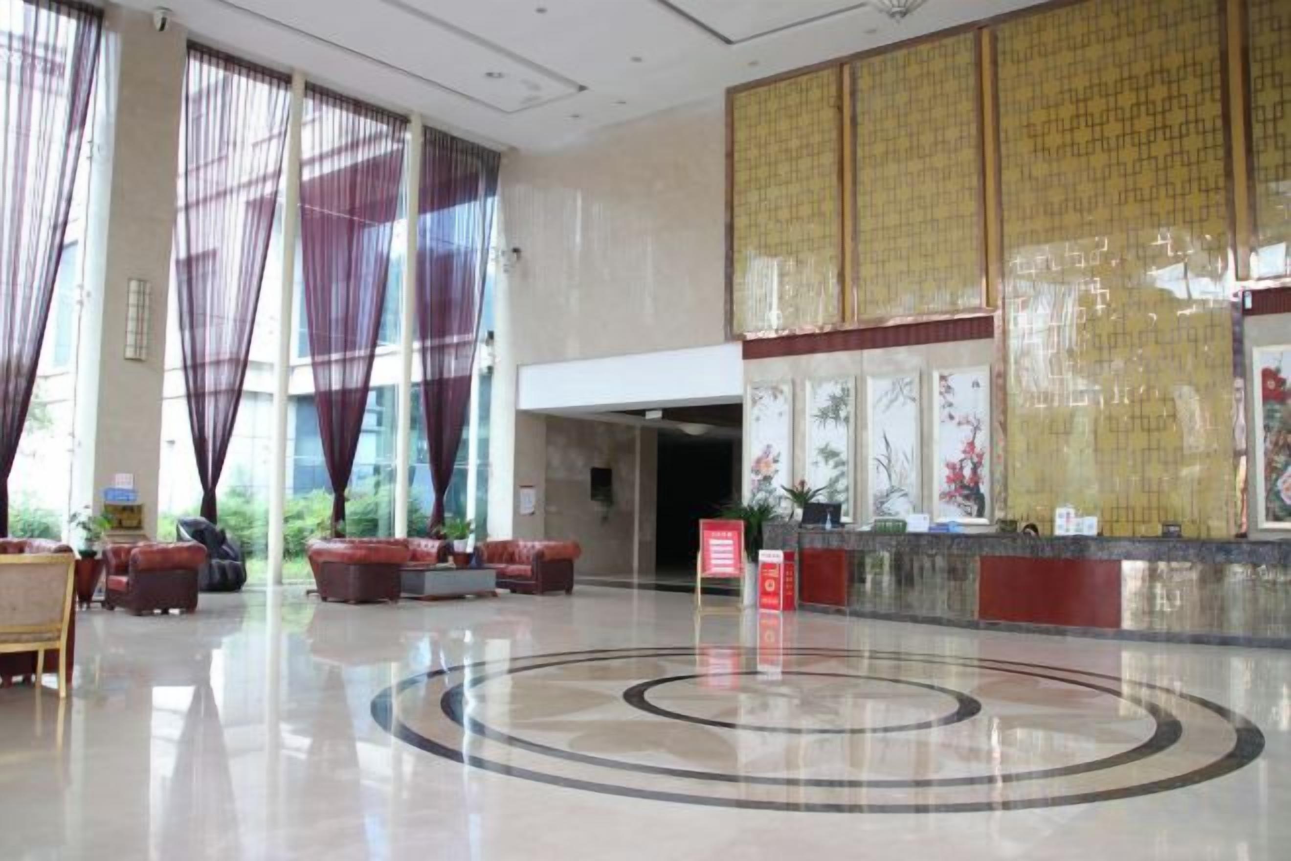 A spacious lobby with a reception desk, seating area, and large windows.